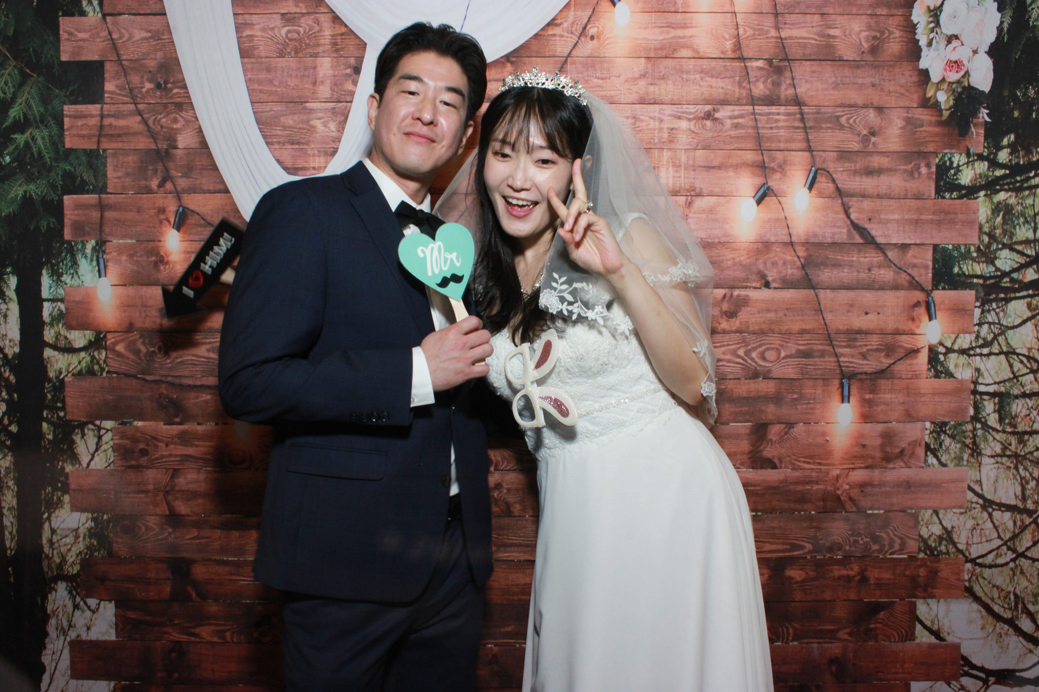 Wedding couple at the Squared Booth — rustic wood backdrop with mint heart sign